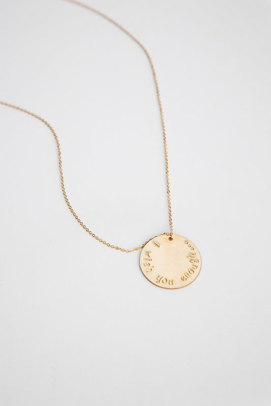 A 25.4 mm 14k gold filled disc hung on a 14k gold cable link chain necklace lays on a white background.
