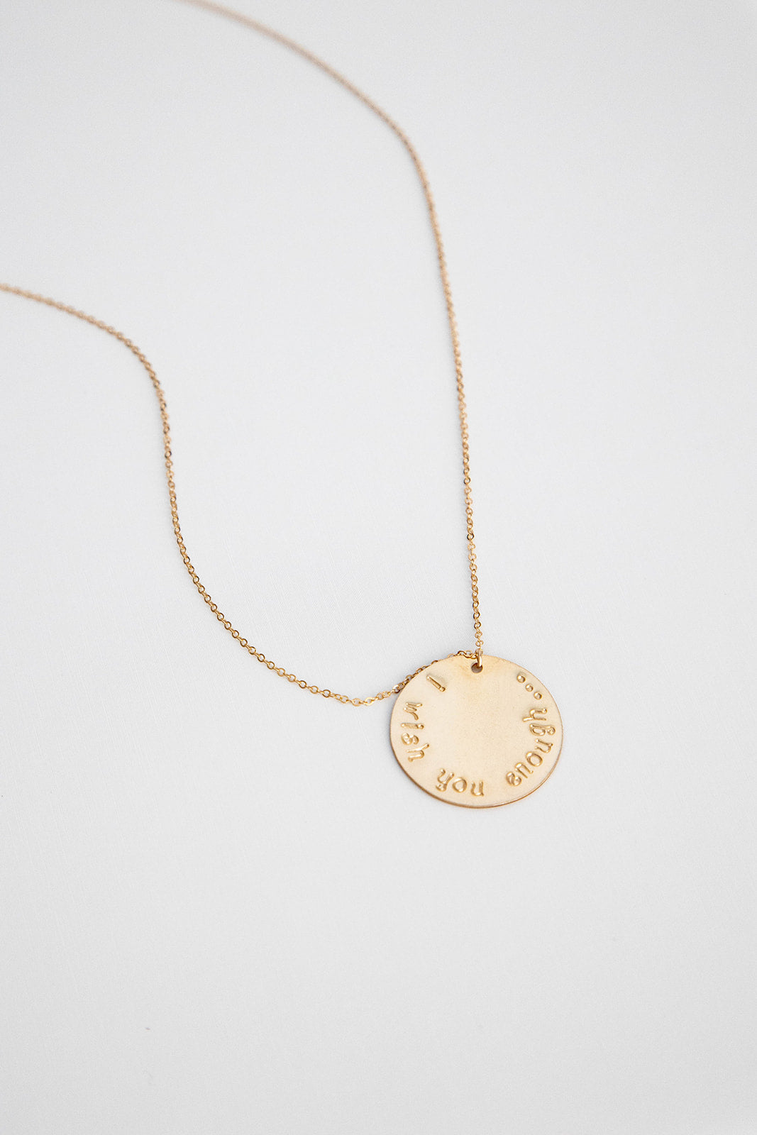 A 25.4 mm 14k gold filled disc hung on a 14k gold cable link chain necklace lays on a white background.